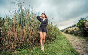 Молодая девушка азиатка стоит у зеленой травы