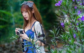 Молодая азиатка с фотоаппаратом в парке