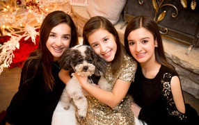 Три улыбающихся девушки с собакой на новый год