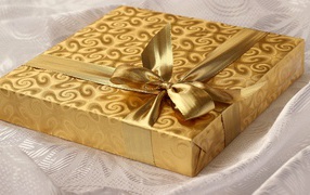 Beautiful golden box with a gift on the bed