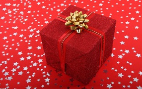 Большой подарок с бантом на красном фоне со звездами 