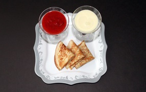 Блинчики с вареньем и сметаной на столе на Масленицу