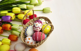 Basket of colored eggs with a bouquet of tulips