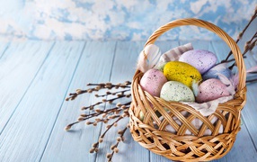 Корзина разноцветных крашеных яиц с ветками вербы на Пасху 2021 