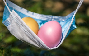 Два крашеных пасхальных яйца в маске от коронавируса