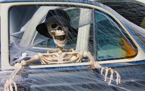 Skeleton in a car with spider webs decor for Halloween holiday