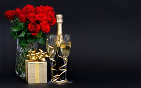 Bouquet of red roses, gift and champagne for March 8