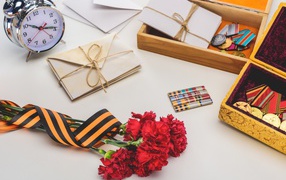 Букет красных гвоздик, ордена и часы на День победы 9 мая