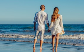 Влюбленная пара гуляет по берегу моря 
