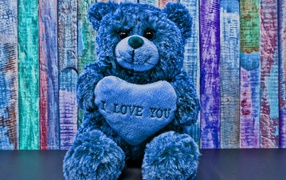 Синий медведь с сердцем на фоне забора