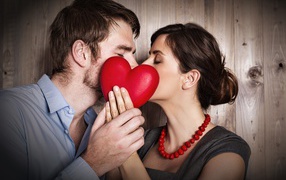 Поцелуй влюбленной пары за красным сердцем