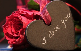 Каменное сердце с ленточкой на столе с розой 