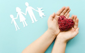 Плетеное сердце в руках на голубом фоне