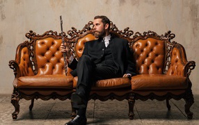 Солидный мужчина в костюме сидит на диване