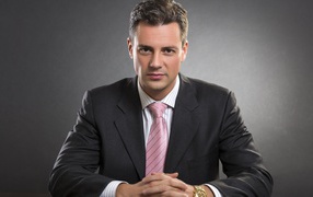 Деловой мужчина в костюме на фоне серой стены 