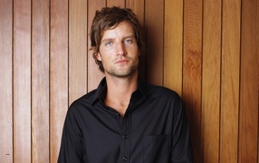 Красивый мужчина в черной рубашке на деревянном фоне