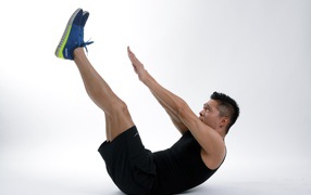 Мужчина спортсмен качает пресс на белом фоне