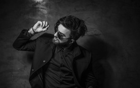 Мужчина в черном костюме на фоне стены