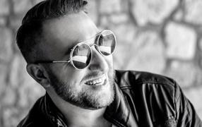 Улыбающийся брутальный мужчина в черных очках