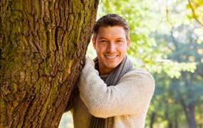 Smiling man standing by the tree