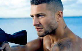 Сильный голубоглазый мужчина с винтовкой в руках 