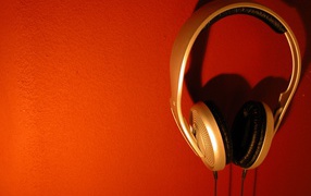 Большие золотые наушники на оранжевом фоне 