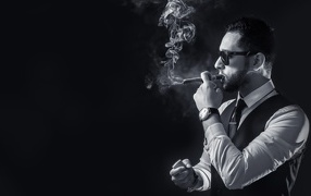 Мужчина с сигарой в руке на черном фоне 
