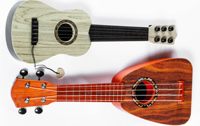 Two small ukulele guitars on a white background