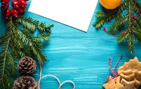 Еловые ветки с печеньем, шишками и декором на синем фоне