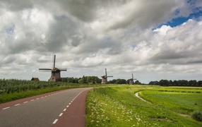 Старые мельницы у дороги под небом с густыми облаками
