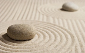 Большой серый камень на песке с кругами 