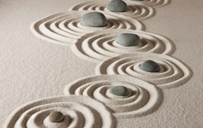 Small gray stones with circles in the sand