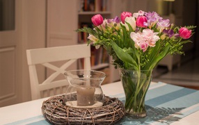 Красивый букет ярких цветов на столе со свечой