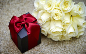 Bouquet of white roses with black gift on the table