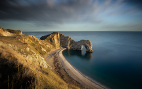 Арка в утесе в море в лучах солнца 