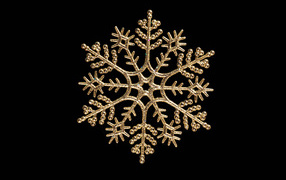 Красивая золотистая снежинка на черном фоне