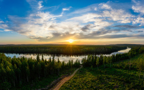 Dawn of the bright sun over the green forest and the river