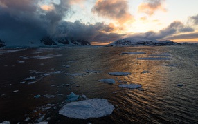 Льдины в воде у покрытых снегом гор в тумане