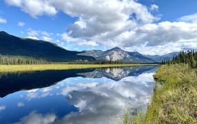 Небо с белыми облаками отражается в реке 