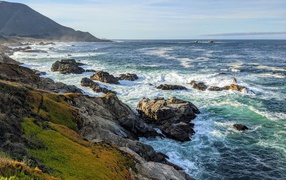 Голубая морская вода омывает камни на берегу 