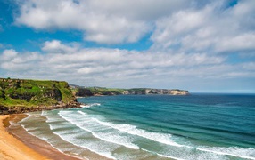 Спокойные волны на берегу залива под голубым небом с облаками