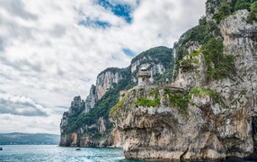 Высокие скалы у моря под белыми облаками 