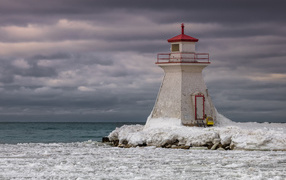 Lighthouse on an ice-covered beach by the sea