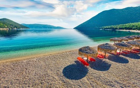 Sun loungers stand on the shore of the lake near the mountains