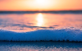 Белая морская пена с пузырям на закате