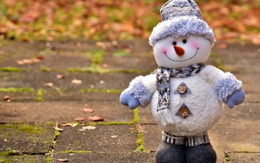 A toy snowman stands on the asphalt