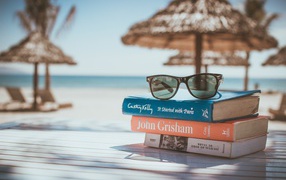 Books and glasses lie on the table on the beach