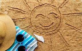 Нарисованное на песке солнце со шляпой и очками летом