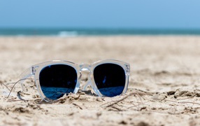 Sunglasses lie on the sand on the beach in summer