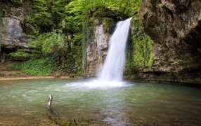 Водопад стекает с крутой горы в озеро 